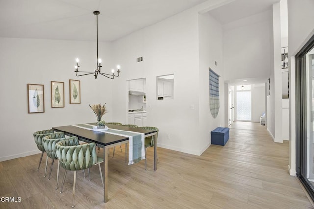 dining area with a chandelier, high vaulted ceiling, and light wood-type flooring