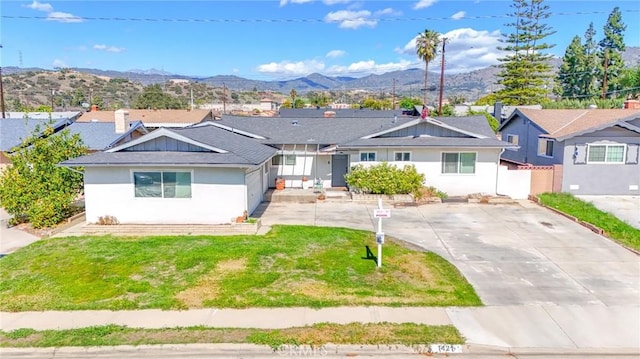 ranch-style home with concrete driveway, a front lawn, fence, and a mountain view