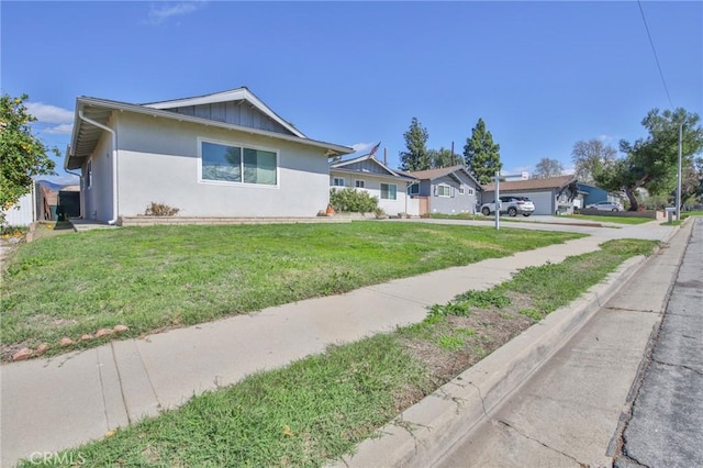 single story home with a front lawn, board and batten siding, and stucco siding