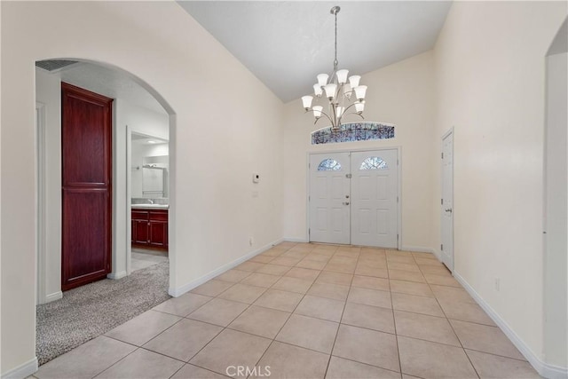 foyer with vaulted ceiling, light tile patterned flooring, and an inviting chandelier