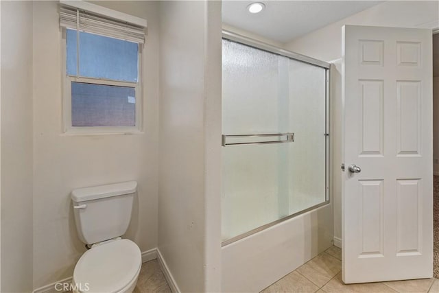 bathroom with tile patterned flooring, toilet, and combined bath / shower with glass door