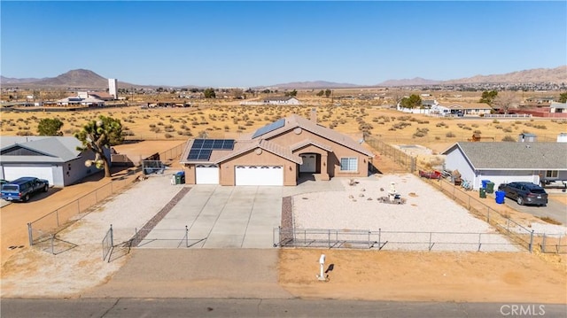 view of front facade featuring a garage, a mountain view, and solar panels