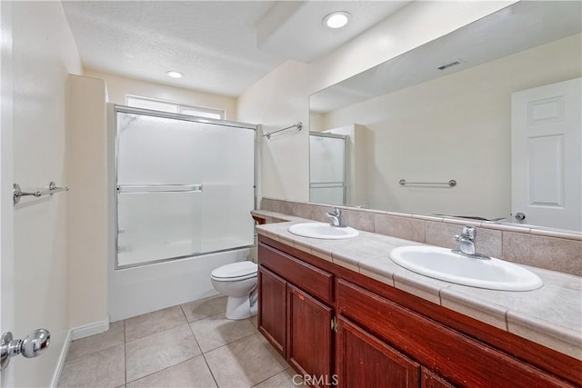 full bathroom featuring bath / shower combo with glass door, vanity, tile patterned floors, and toilet