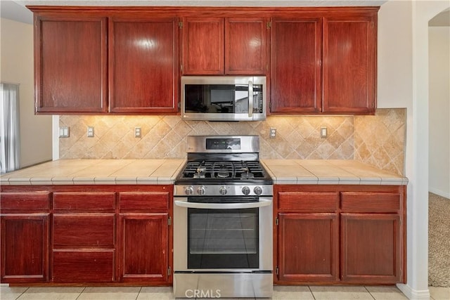 kitchen featuring tasteful backsplash, tile countertops, and stainless steel appliances