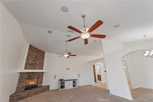 unfurnished living room featuring high vaulted ceiling, a stone fireplace, ceiling fan with notable chandelier, and light colored carpet