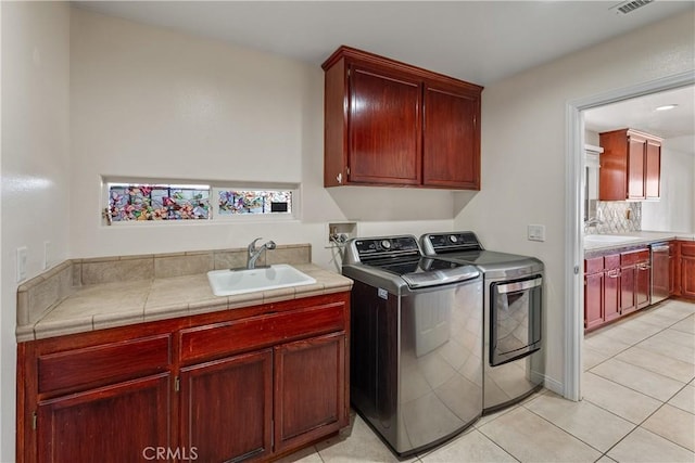 laundry area with cabinets, sink, light tile patterned floors, and washing machine and clothes dryer