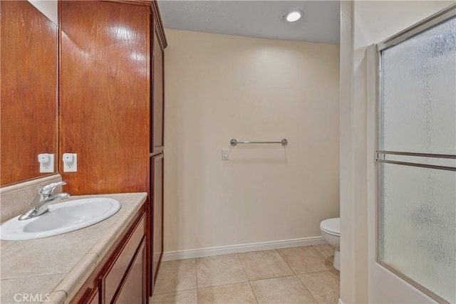 bathroom featuring tile patterned flooring, vanity, a shower with shower door, and toilet