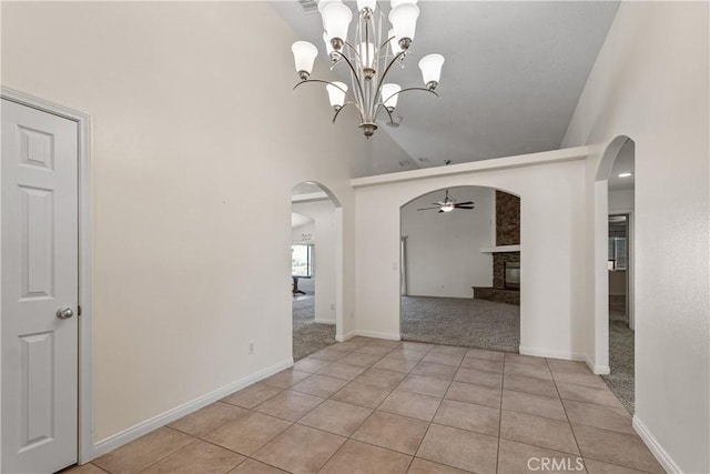 tiled empty room with high vaulted ceiling, a fireplace, and ceiling fan