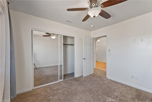 unfurnished bedroom featuring light colored carpet, a textured ceiling, ceiling fan, and a closet