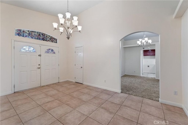 entrance foyer with an inviting chandelier, a towering ceiling, and light tile patterned flooring