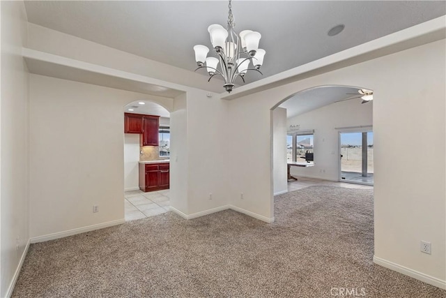 carpeted empty room featuring vaulted ceiling and ceiling fan with notable chandelier