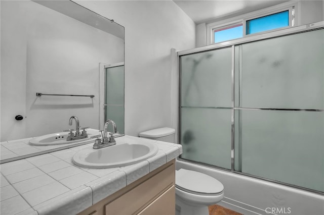 full bathroom with vanity, enclosed tub / shower combo, and toilet