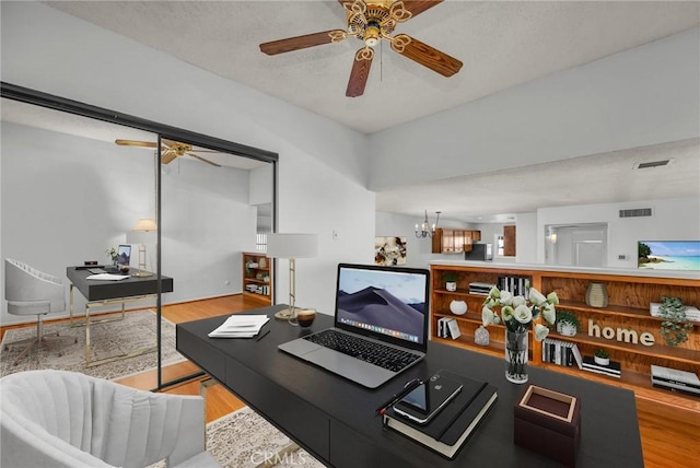 living room featuring ceiling fan with notable chandelier and light wood-type flooring