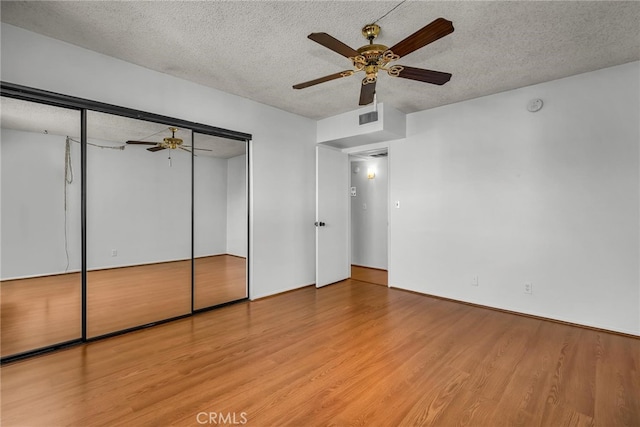 unfurnished bedroom featuring ceiling fan, a closet, light hardwood / wood-style flooring, and a textured ceiling