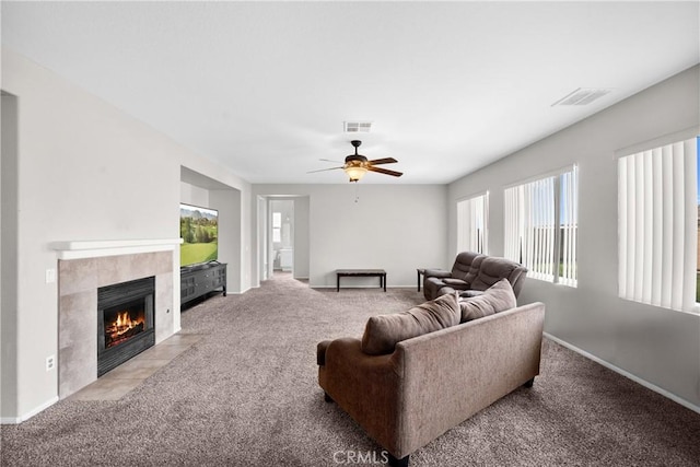 living area with a ceiling fan, light colored carpet, visible vents, and a fireplace