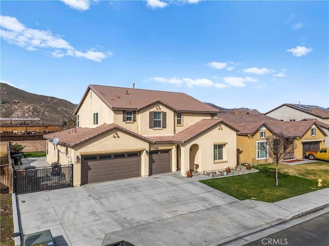 mediterranean / spanish-style home featuring an attached garage, a mountain view, a tile roof, driveway, and a front yard