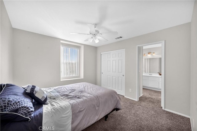 carpeted bedroom with a closet, visible vents, ensuite bathroom, a ceiling fan, and baseboards