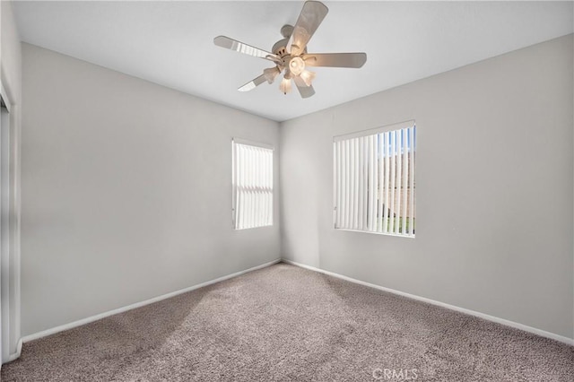 carpeted spare room with ceiling fan and baseboards