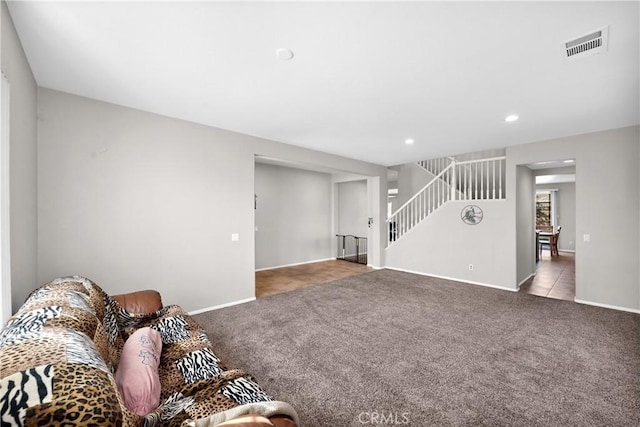 living room with light carpet, baseboards, stairs, and visible vents