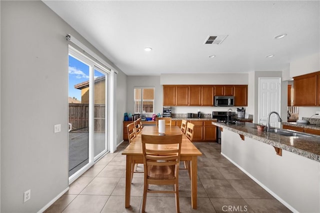 kitchen featuring stainless steel appliances, brown cabinets, visible vents, and a sink