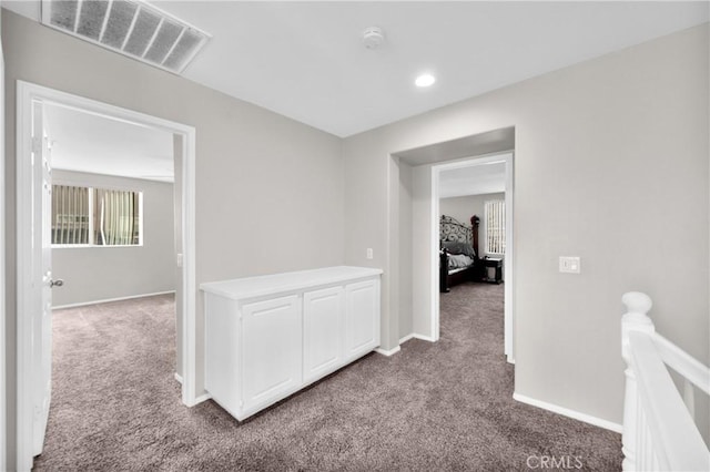 corridor with light carpet, an upstairs landing, visible vents, and baseboards