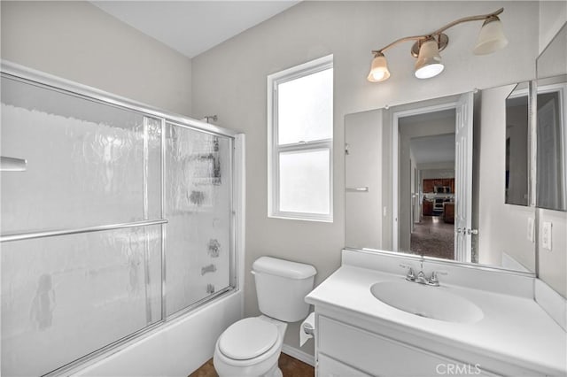 bathroom featuring toilet, bath / shower combo with glass door, and vanity