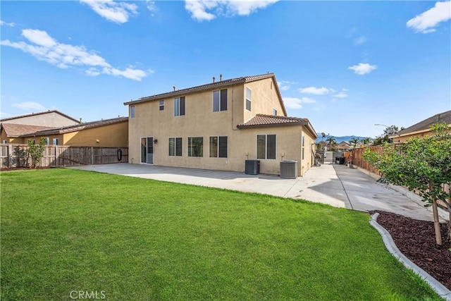 rear view of house with a patio area, a fenced backyard, a lawn, and stucco siding