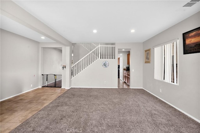 unfurnished living room with stairs, carpet, baseboards, and tile patterned floors