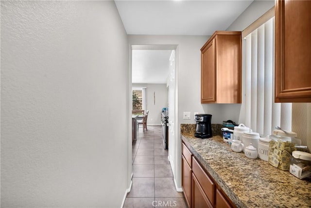 interior space featuring light tile patterned floors, baseboards, and brown cabinets