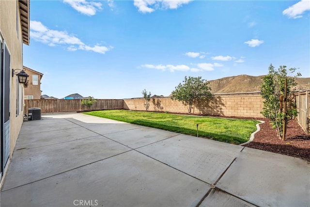 view of patio with a fenced backyard, a mountain view, and central AC