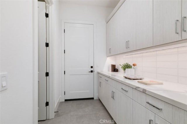 clothes washing area with light tile patterned floors