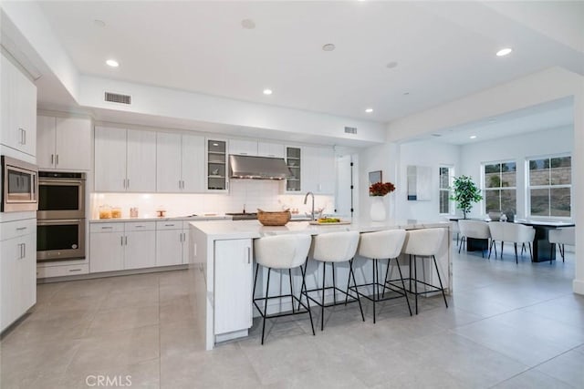 kitchen featuring white cabinetry, a kitchen bar, stainless steel appliances, and a kitchen island