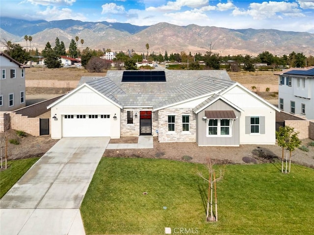 view of front of house with a garage, a mountain view, a front lawn, and solar panels