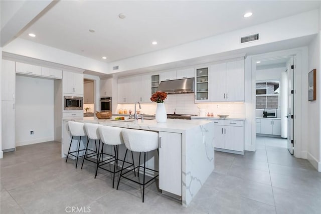 kitchen featuring white cabinetry, sink, backsplash, a kitchen island with sink, and stainless steel appliances