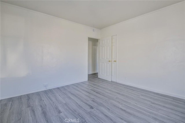 spare room with ornamental molding and light hardwood / wood-style floors