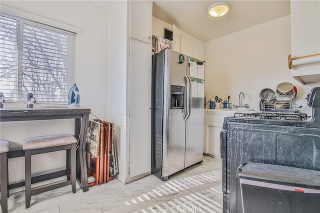 kitchen featuring white cabinetry and stainless steel fridge