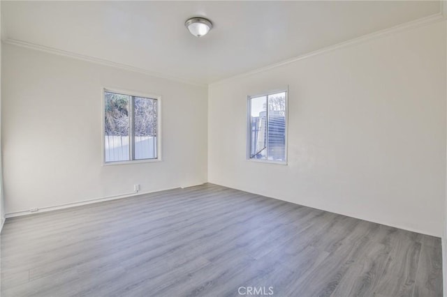 spare room featuring ornamental molding, a healthy amount of sunlight, and light wood-type flooring