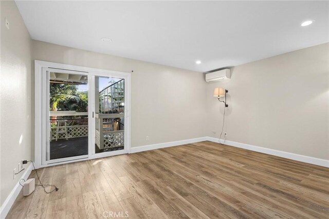 spare room with a wall mounted air conditioner and wood-type flooring