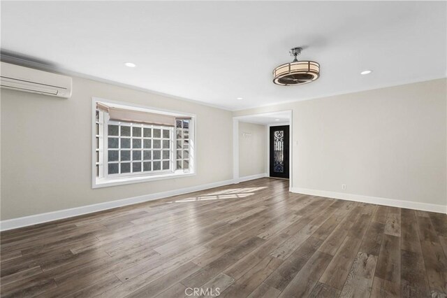 empty room featuring an AC wall unit and dark wood-type flooring