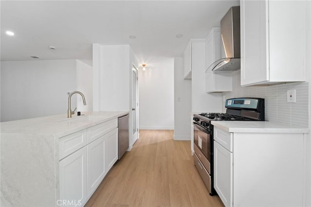 kitchen featuring stainless steel appliances, sink, wall chimney range hood, and white cabinets