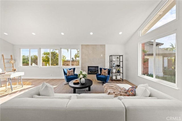 living room with lofted ceiling, plenty of natural light, a tiled fireplace, and wood finished floors