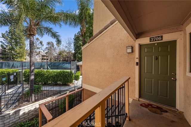 doorway to property featuring stucco siding and fence