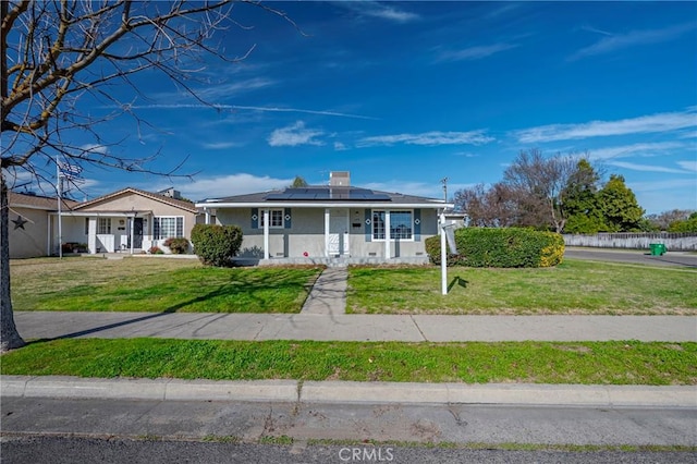 view of front of house with a front lawn, covered porch, and solar panels