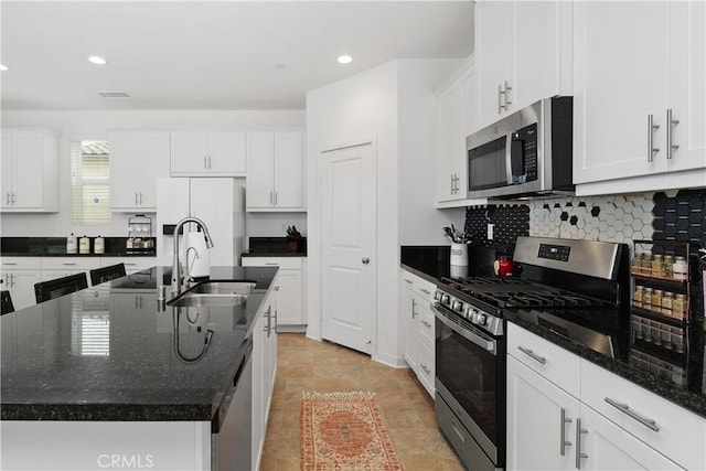 kitchen with appliances with stainless steel finishes, white cabinetry, an island with sink, and a sink