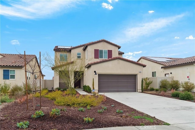 mediterranean / spanish home with roof mounted solar panels, stucco siding, driveway, and fence