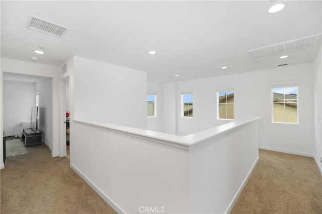 corridor with recessed lighting, visible vents, baseboards, and light colored carpet