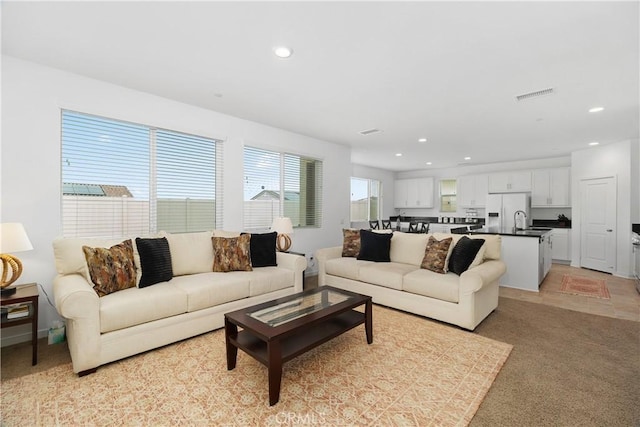 living area featuring recessed lighting, visible vents, and light carpet