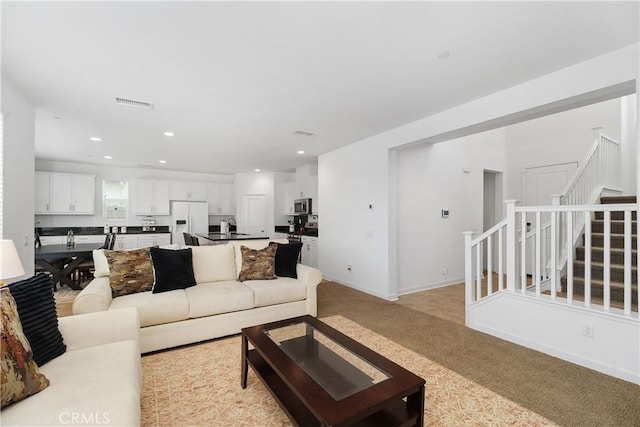 living room with stairway, visible vents, baseboards, recessed lighting, and light carpet