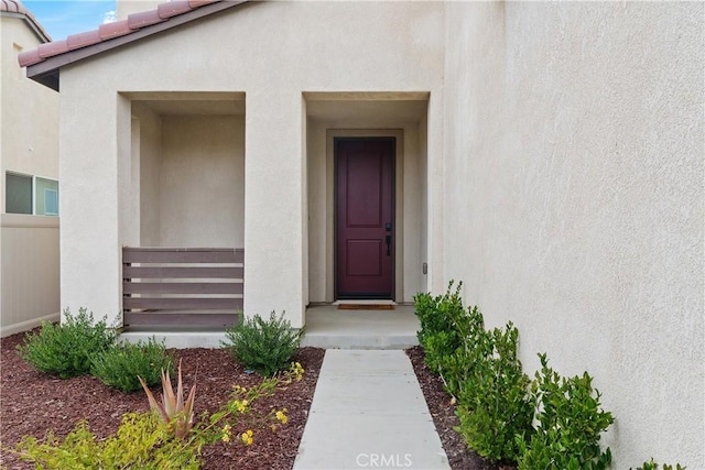 view of exterior entry featuring stucco siding and a tiled roof