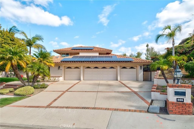 mediterranean / spanish house with a tile roof, a garage, driveway, and stucco siding